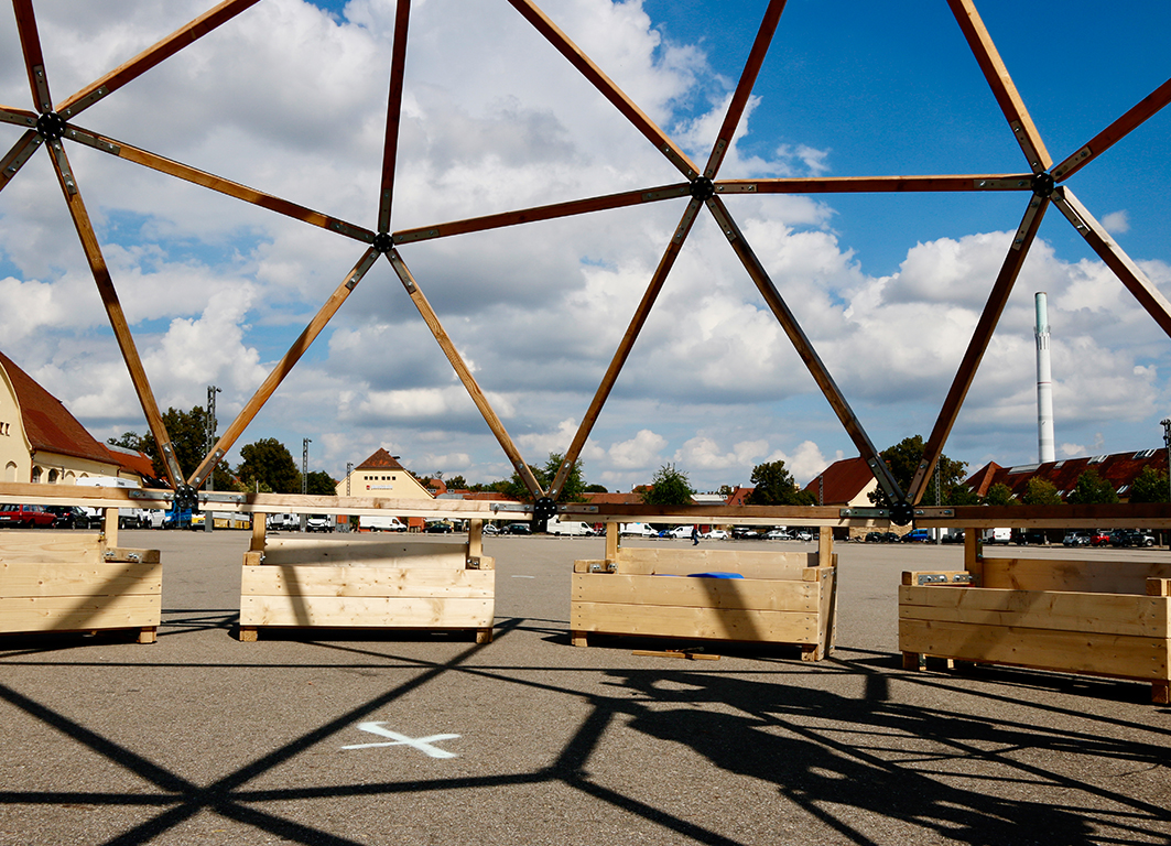 Foto ein Ssonniger grosser Platz mit einer Holzkonstruktion eines Veranstalltungszelts beim Aufbau